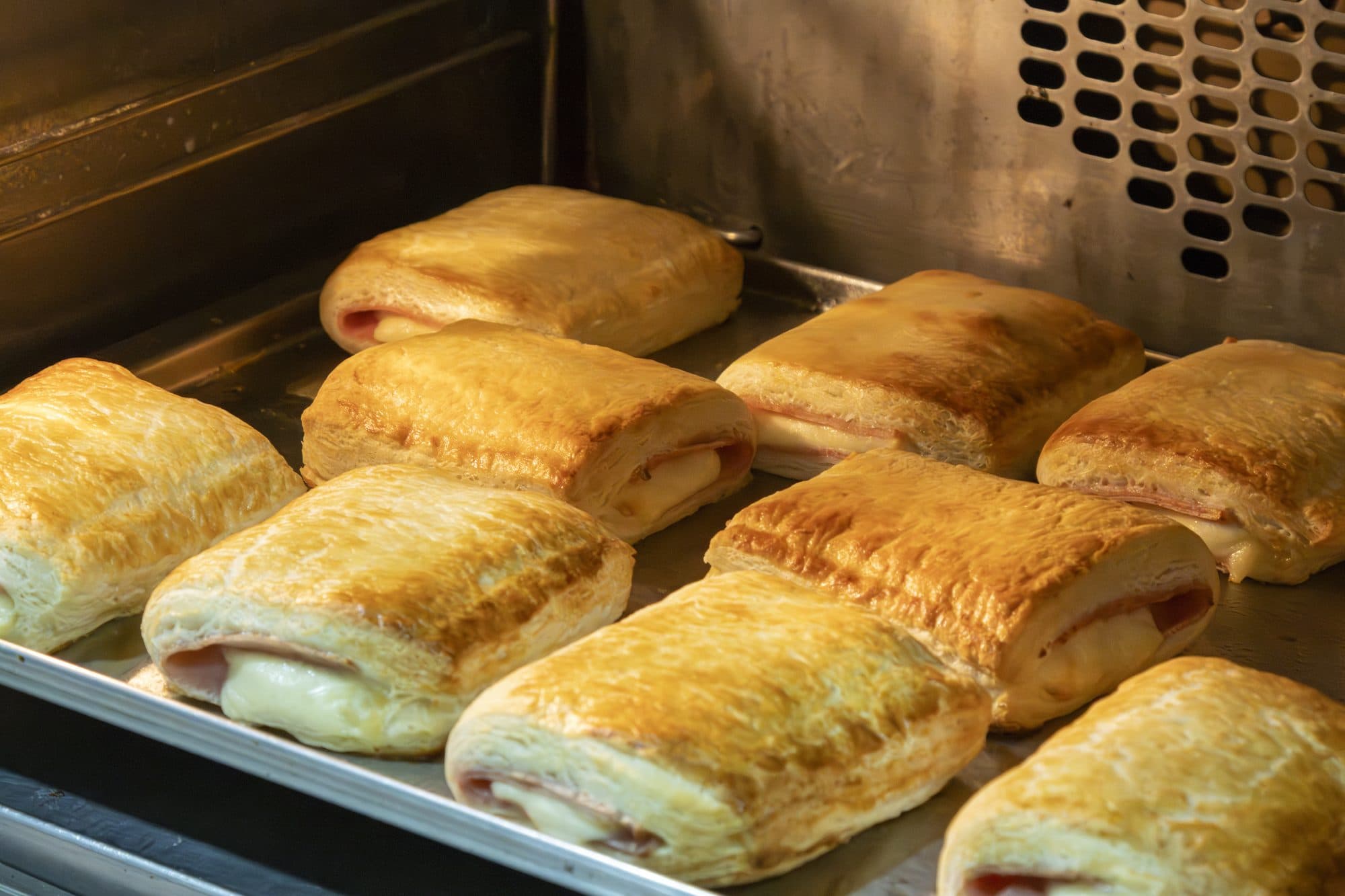 Tabuleiro de folhados de presunto e queijo dentro do forno