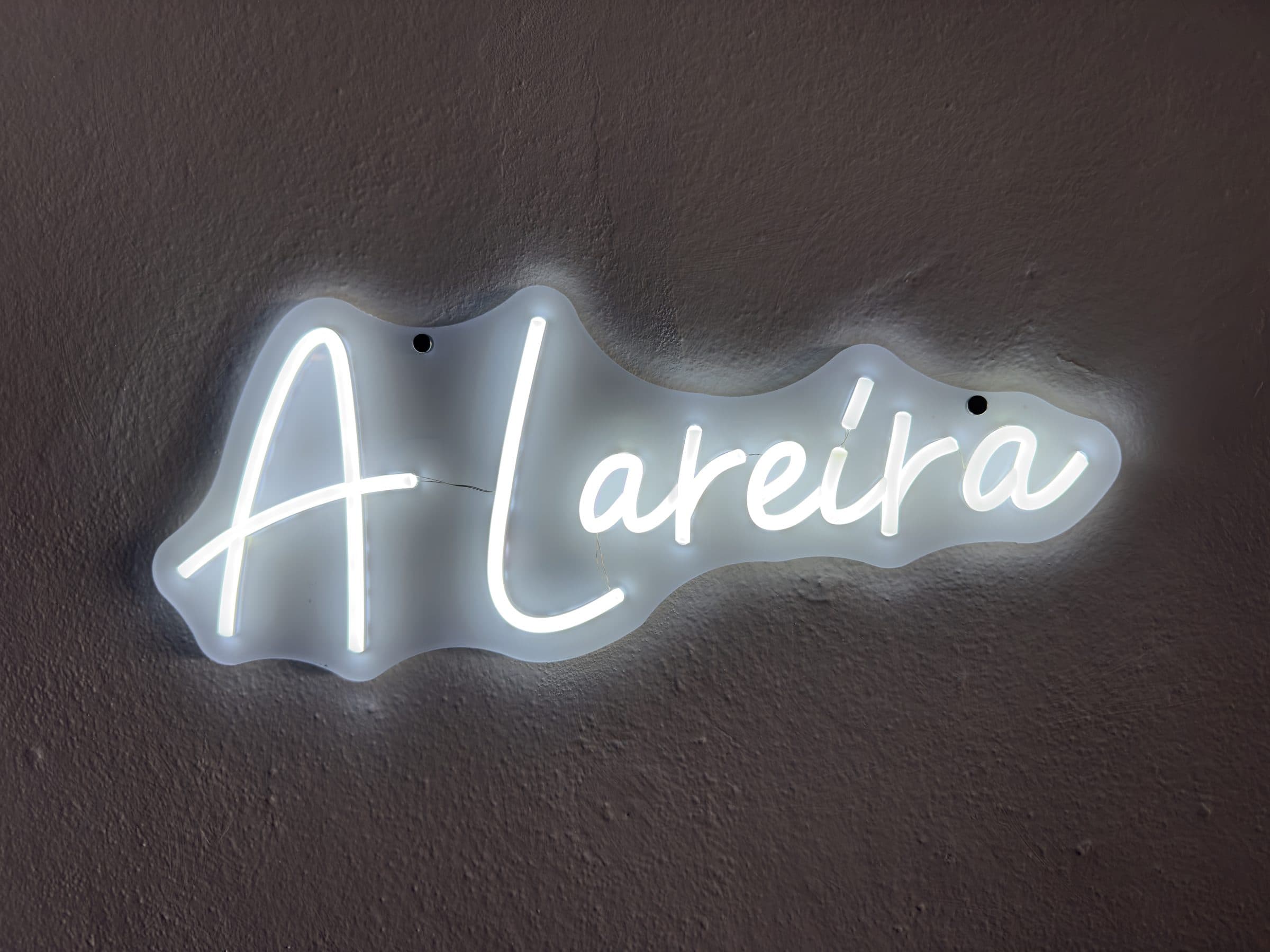 Letreiro luminoso com o nome «A Lareira» na parede do café