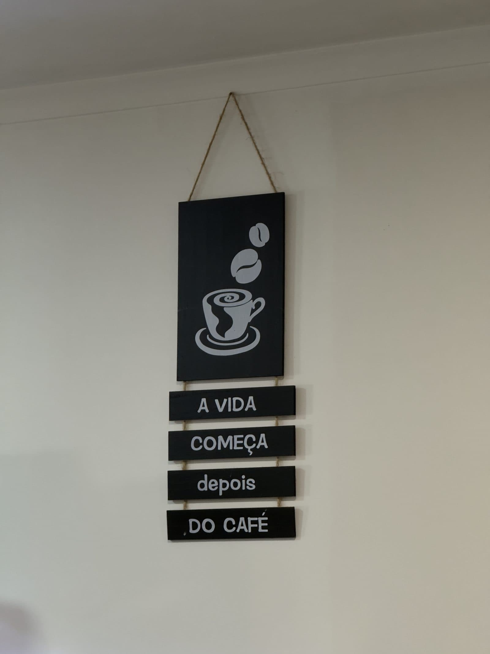 Placa de madeira na parede com a frase «A vida começa depois do café»